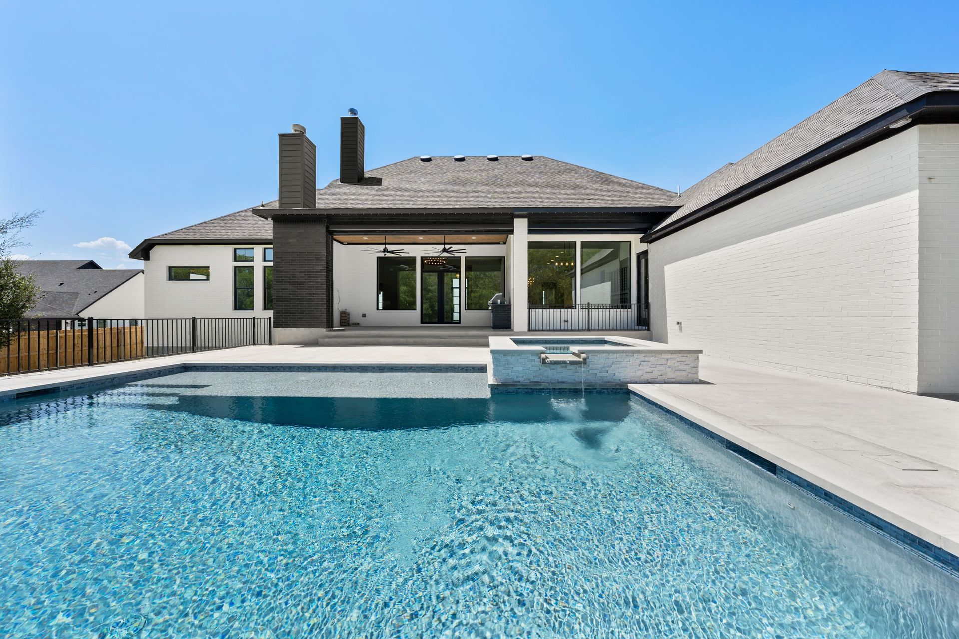 Backyard pool with blue water beside a modern house and patio seating area