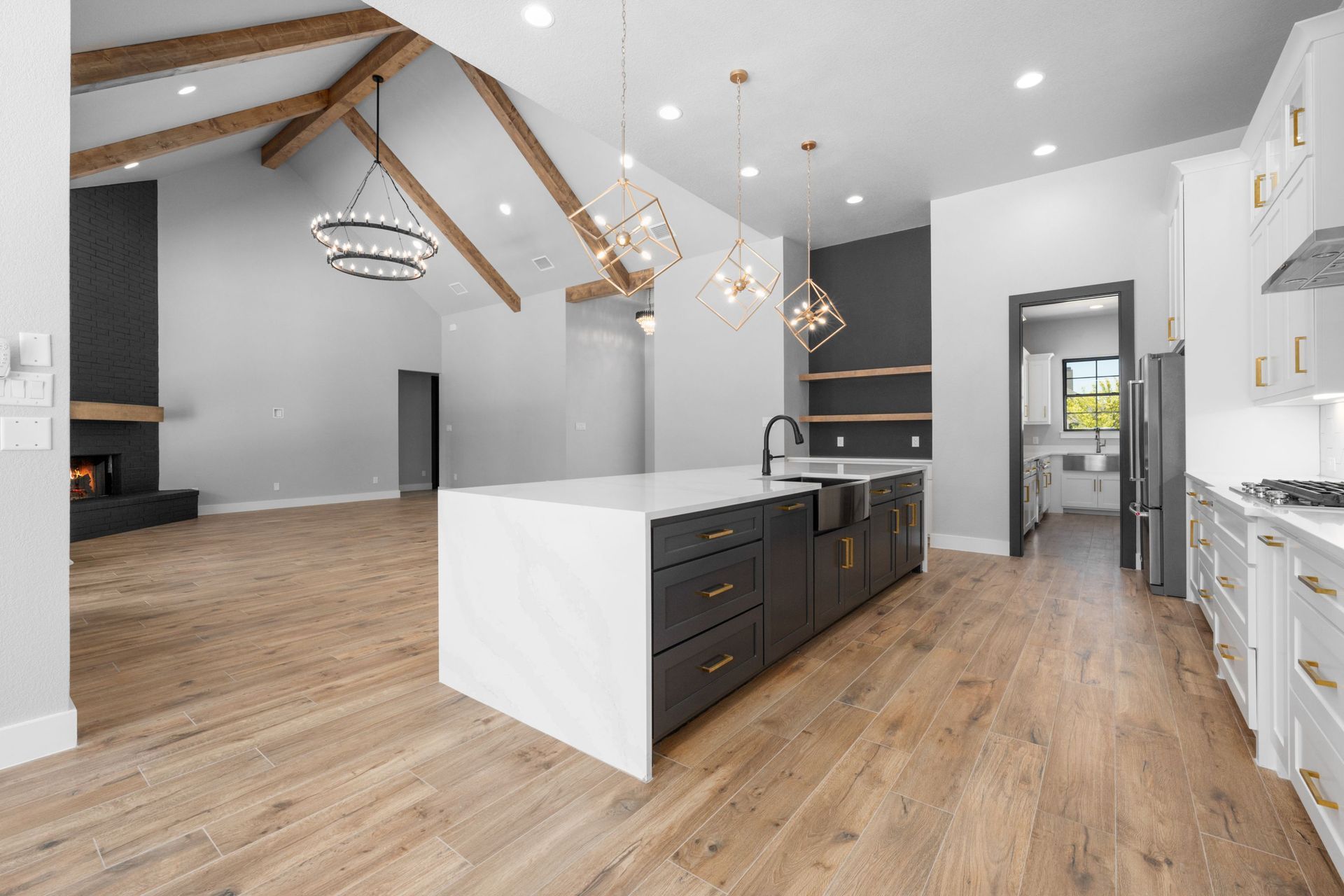 Bright modern kitchen with white island, wood floors, vaulted ceiling, and pendant lights
