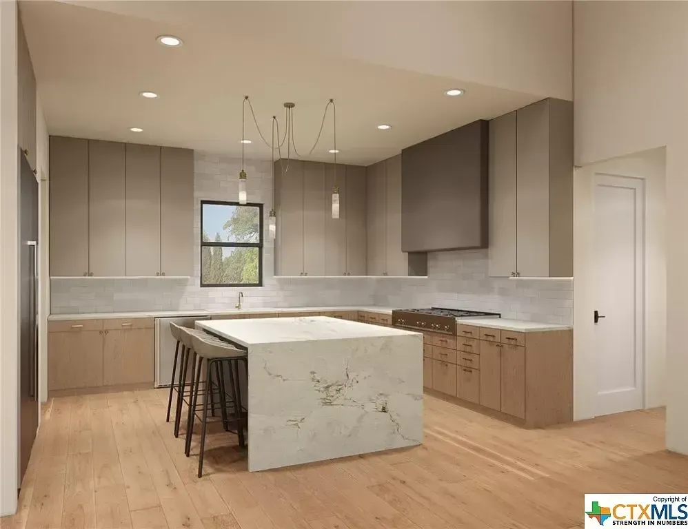 Modern kitchen with wood cabinets, marble island, pendant lights, and light hardwood floors.
