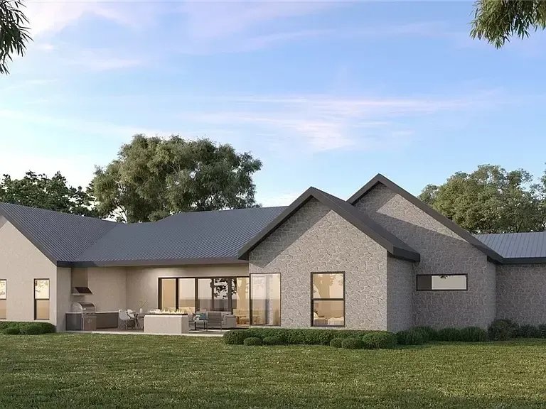 Modern single-story house with gray roof, light brick exterior, and a landscaped lawn at dusk