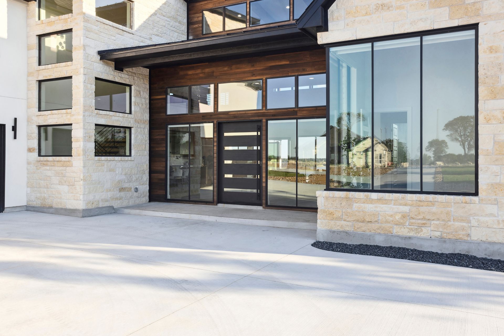 Modern building entrance with glass doors, large windows, and stone facade on a bright day