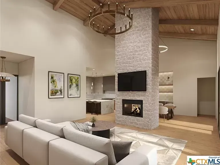 Modern open-concept living room with white sofa, stone fireplace, wall TV, and wood ceiling