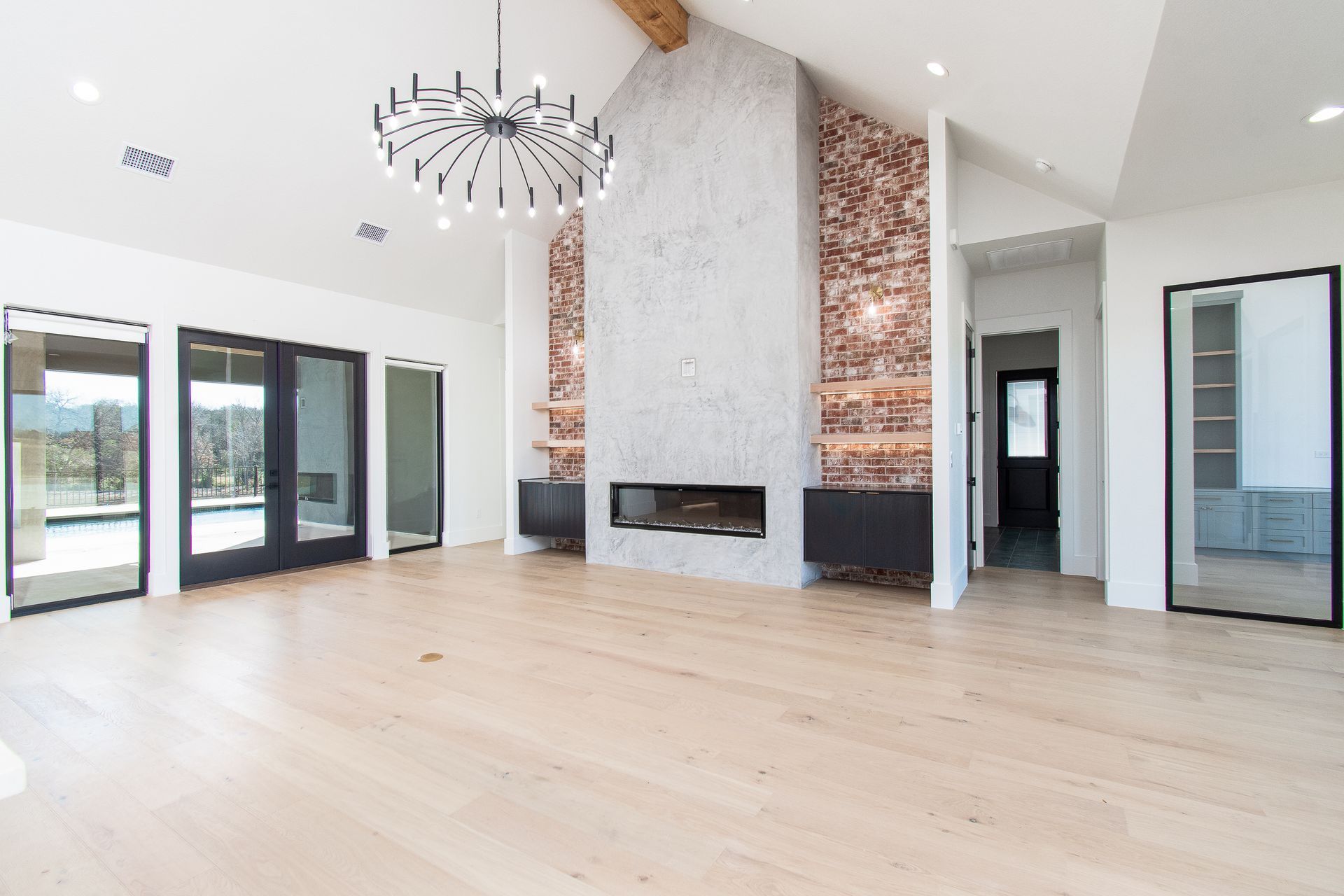 Bright modern living room with light wood floors, fireplace, and large windows and doors