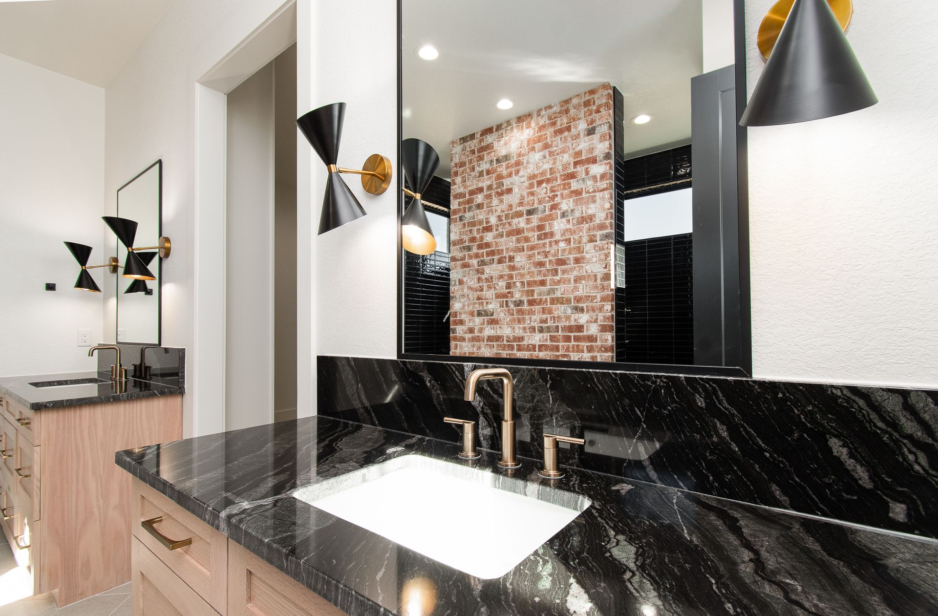 Modern bathroom vanity with black marble countertop, white sink, large mirror, and pendant lights