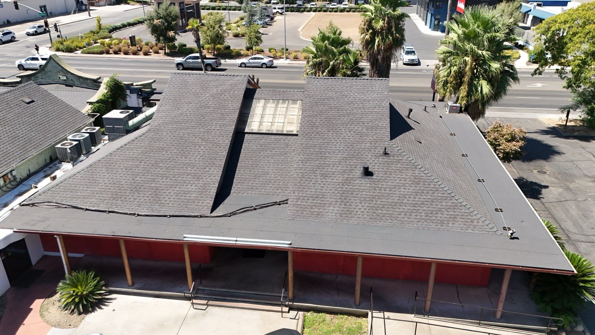 Aerial view of a red building with a dark gray roof and surrounding parking lot
