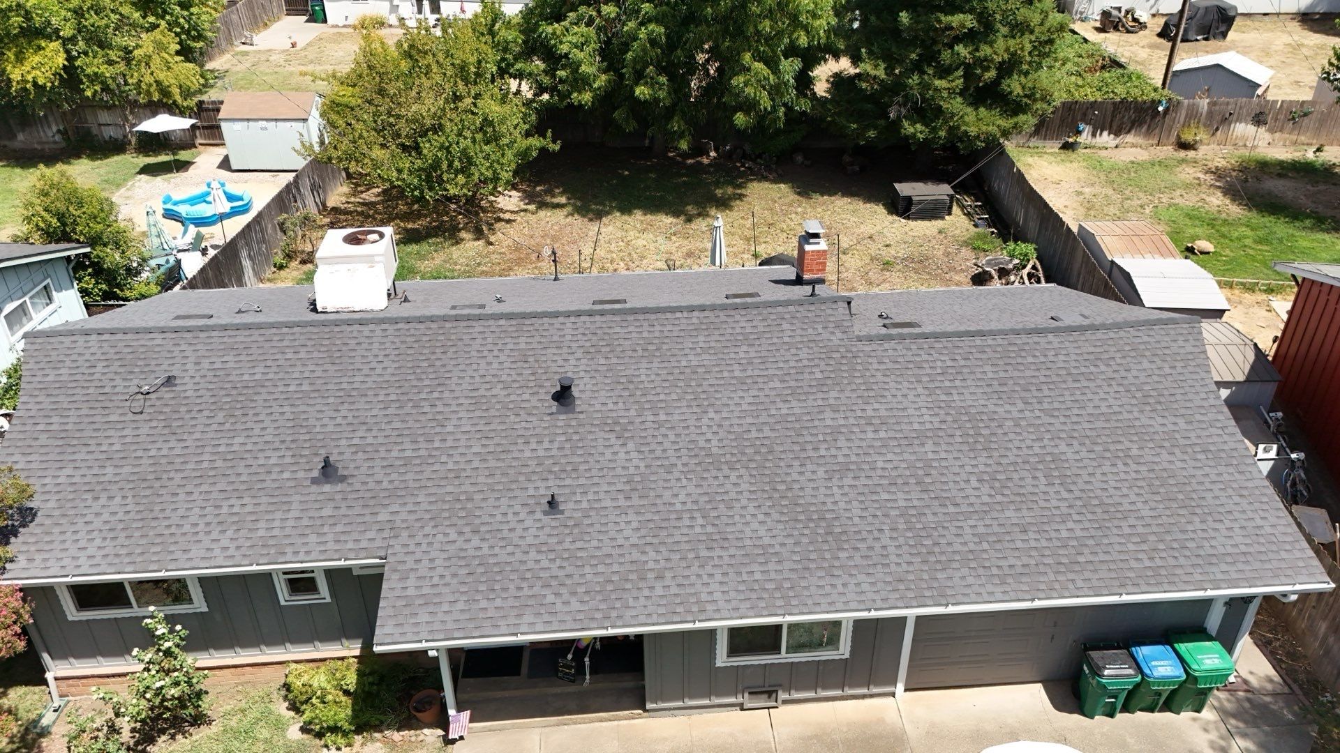 Aerial view of a gray-roofed single-story house with a small front porch and yard.