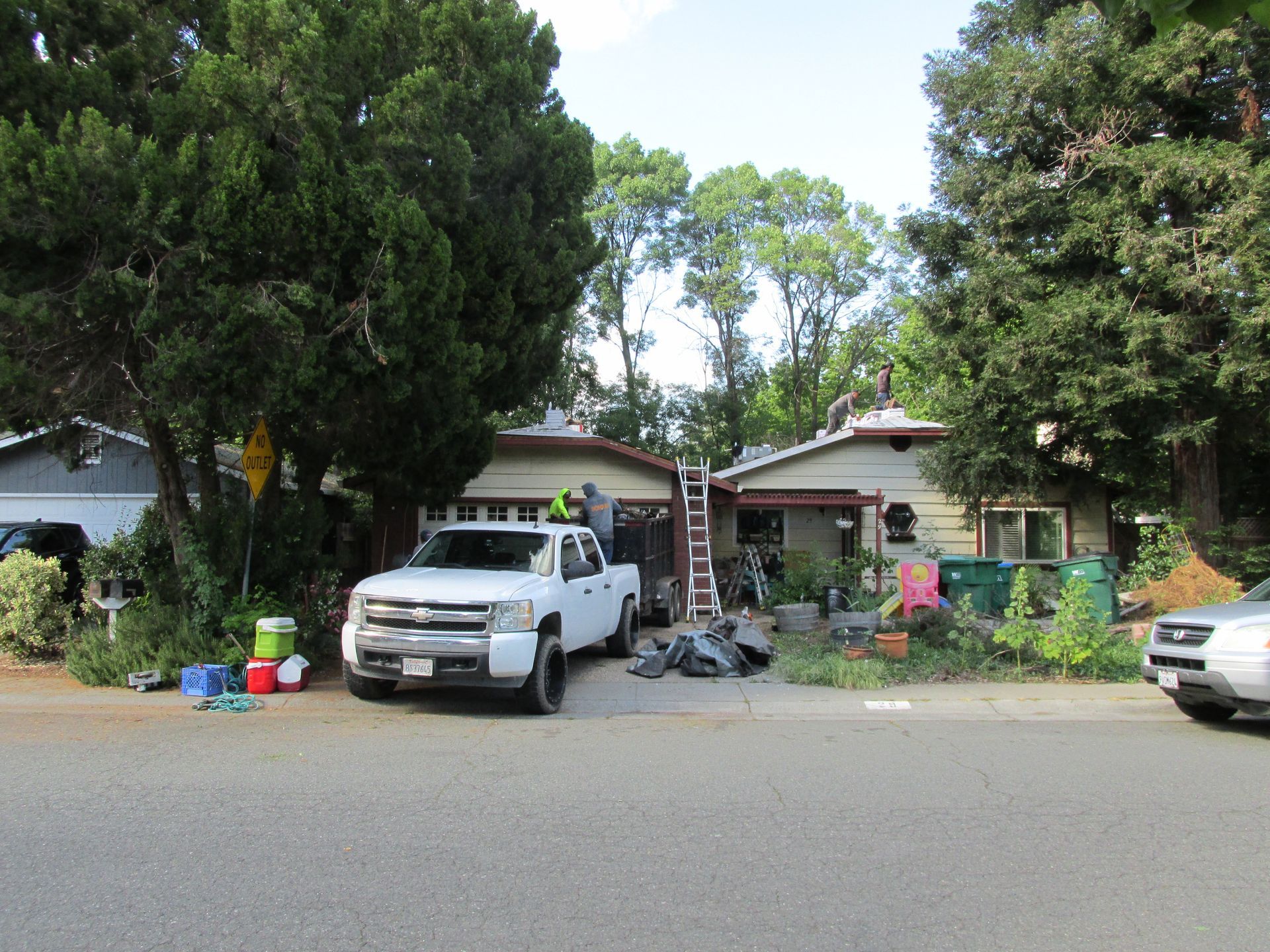 Residential driveway with parked white pickup truck, bicycles, and a house partly hidden by trees