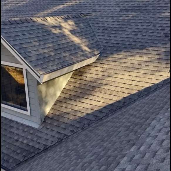 Gray shingle roof with a dormer window and sunlight casting long shadows