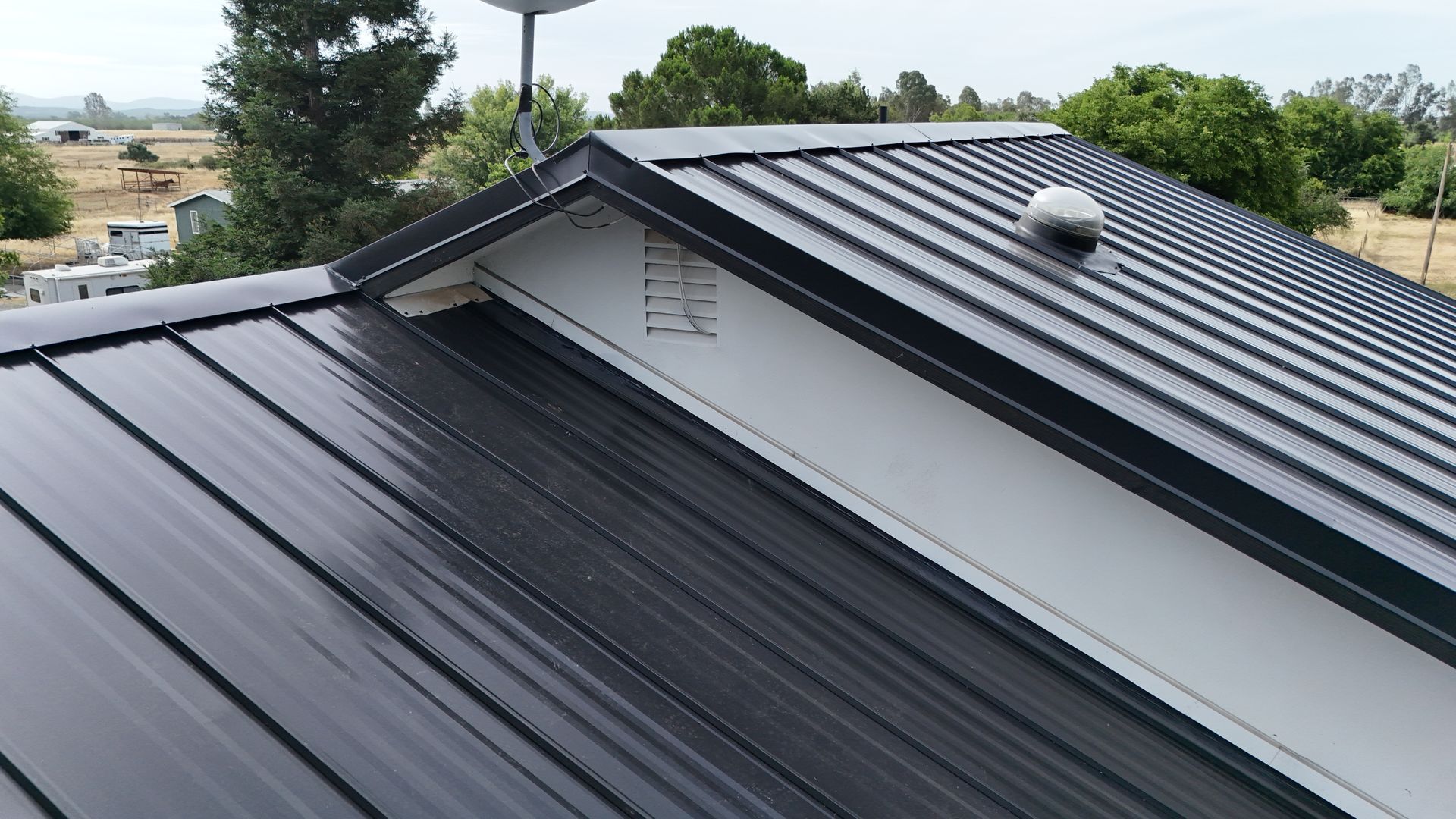 Black metal roof with ridge vent and skylight on a house, viewed from above