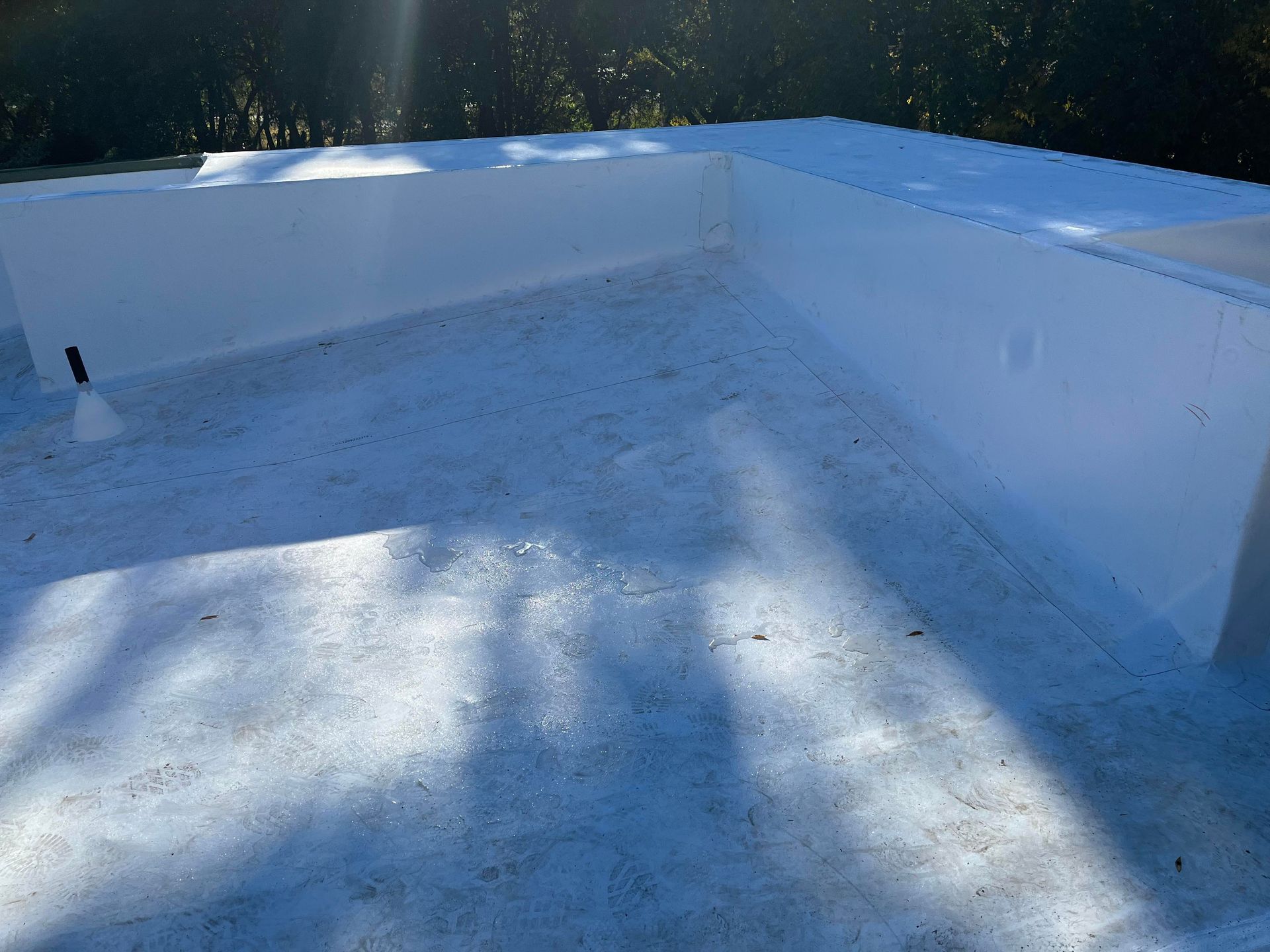 Empty white rooftop covered in snow, with sunlight casting long shadows.