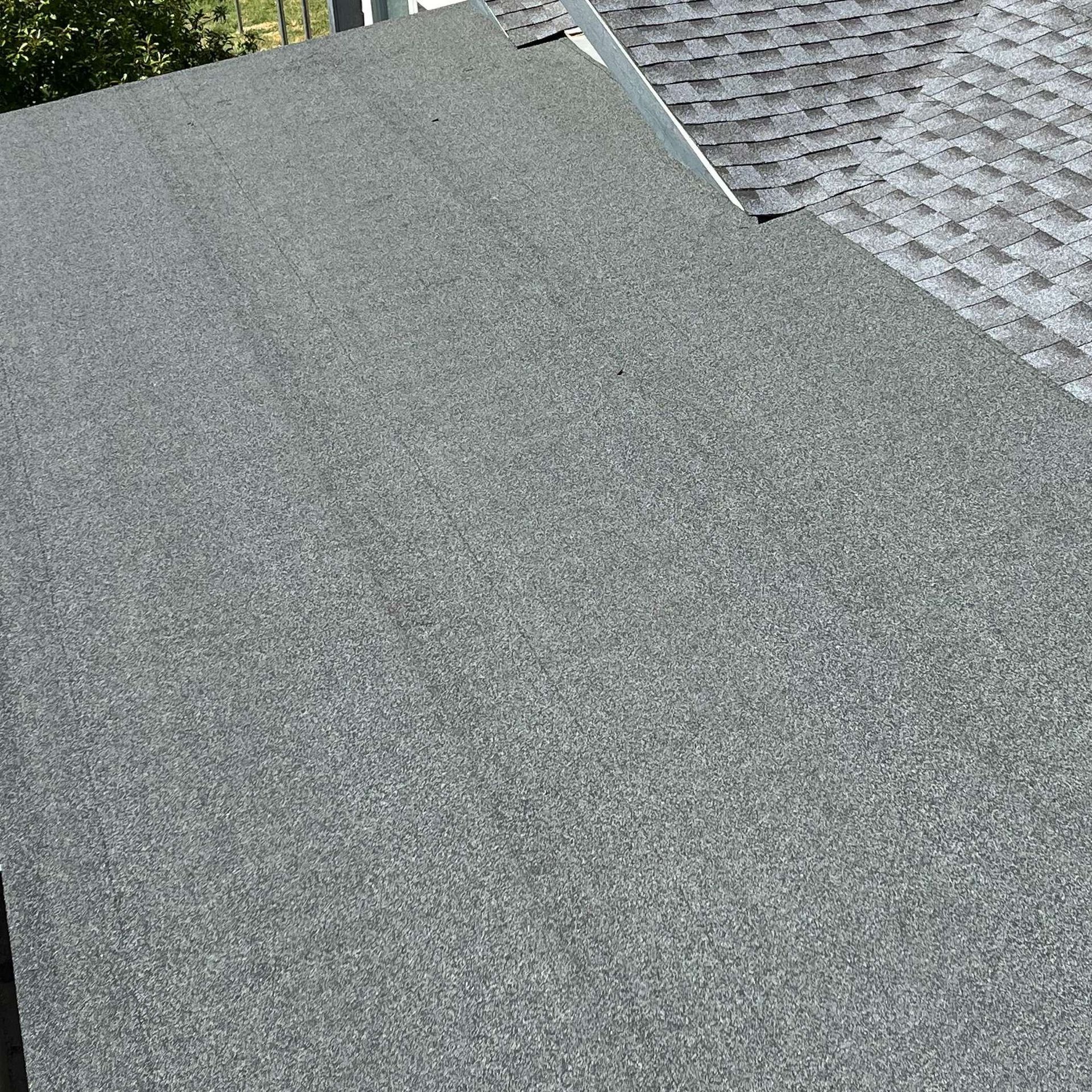 Gray roof shingles beside a darker shingled roof, viewed close up from above