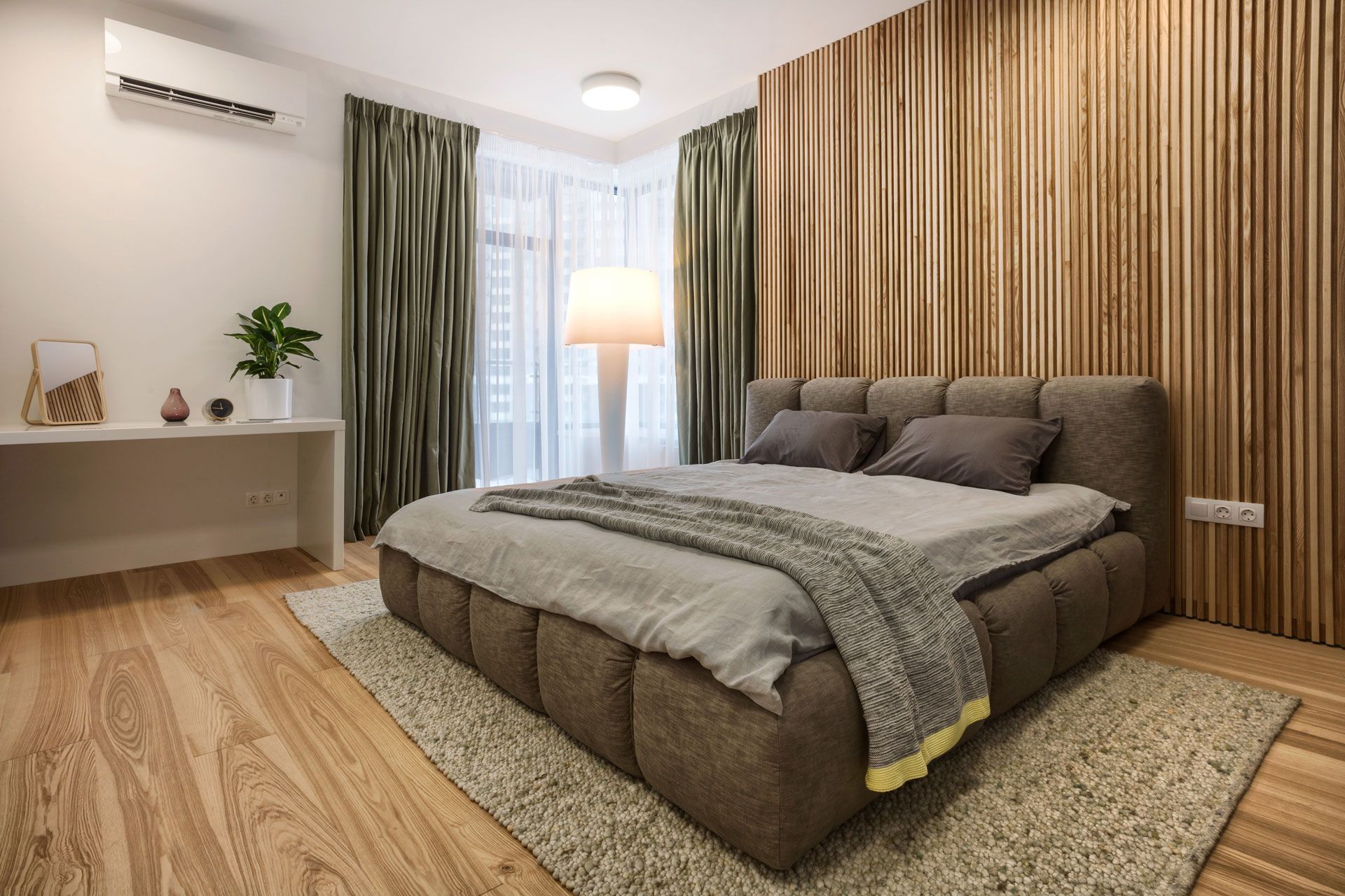 Modern bedroom with a large bed, wood-paneled wall, and floor lamp by the window