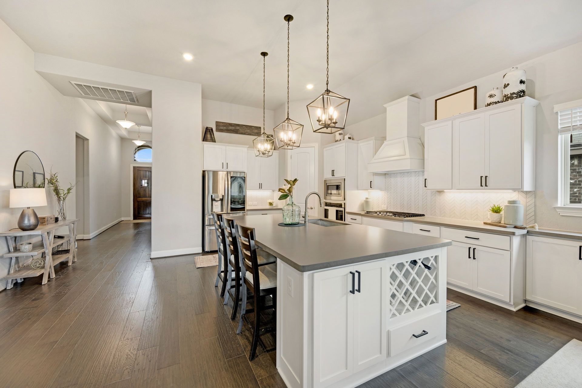 Bright white kitchen with island, pendant lights, and bar stools in an open-plan home