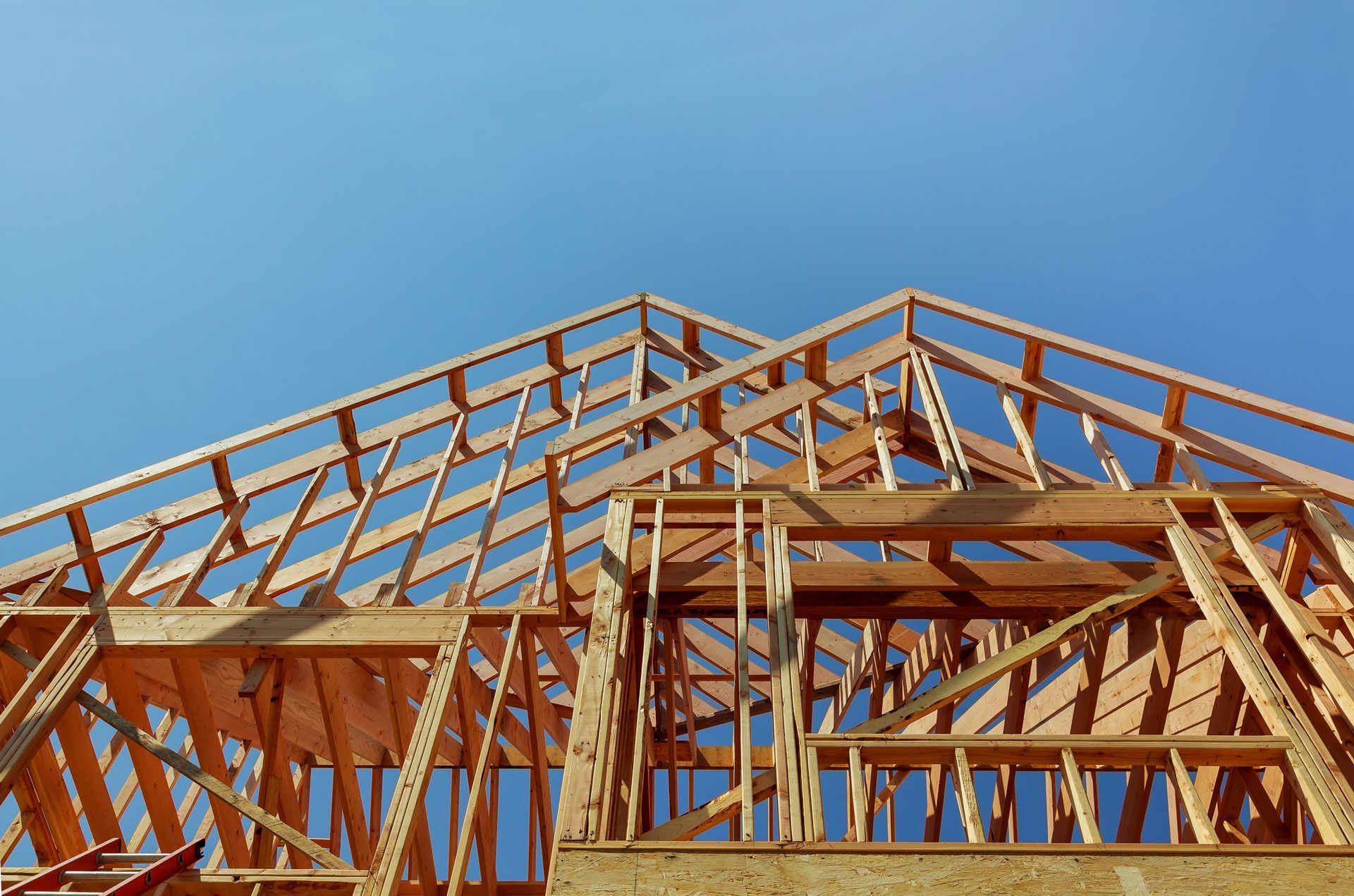 Wooden house frame under construction against a clear blue sky