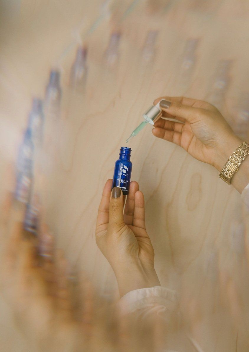 A person is holding a blue bottle with a pipette in their hand.
