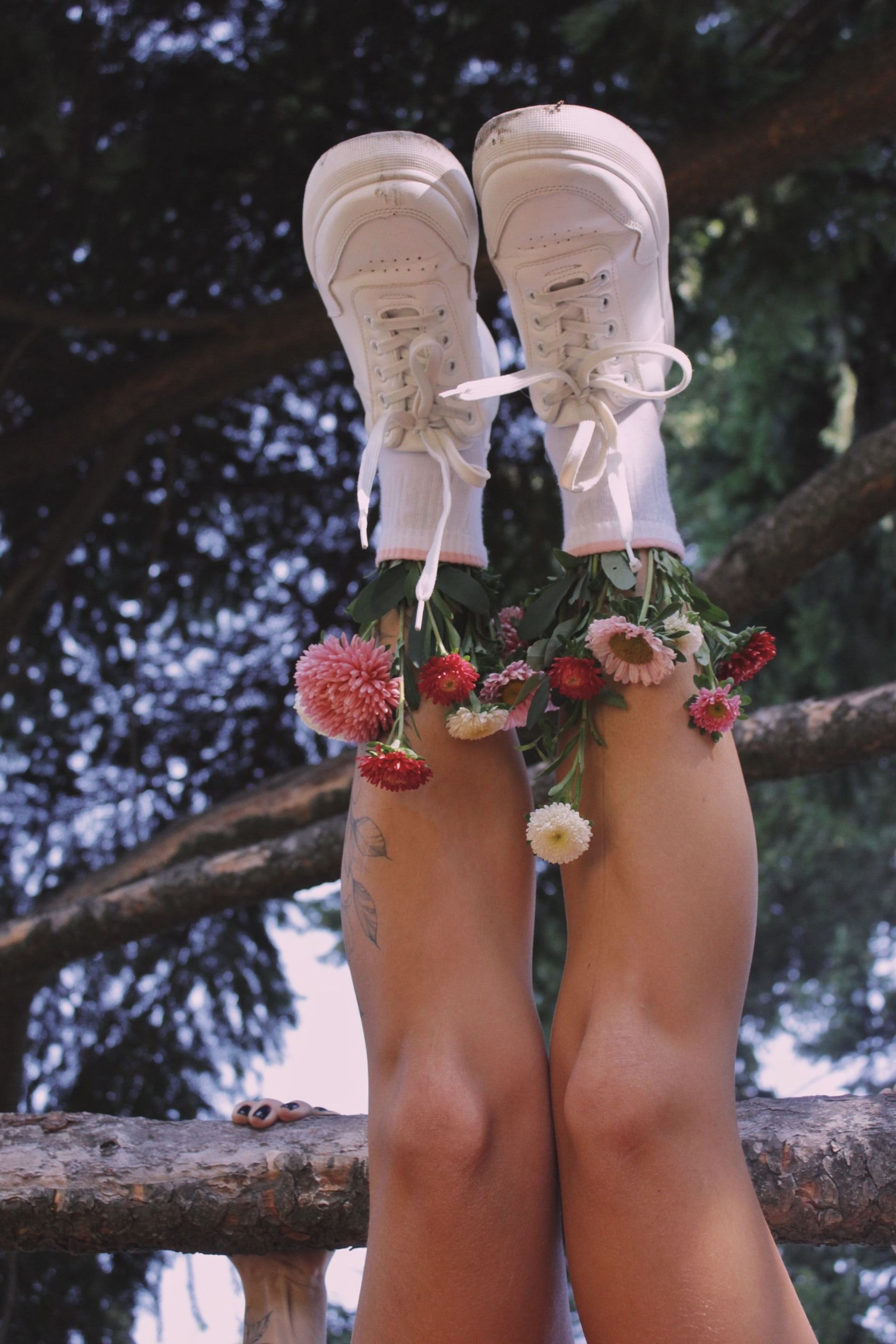 A woman 's legs are covered in flowers and shoes.