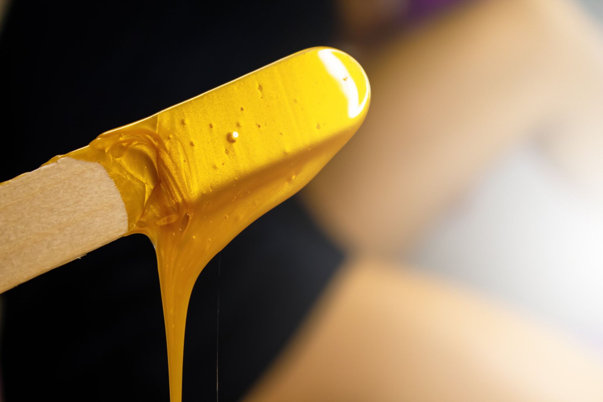 A close up of a wax stick with yellow wax dripping from it