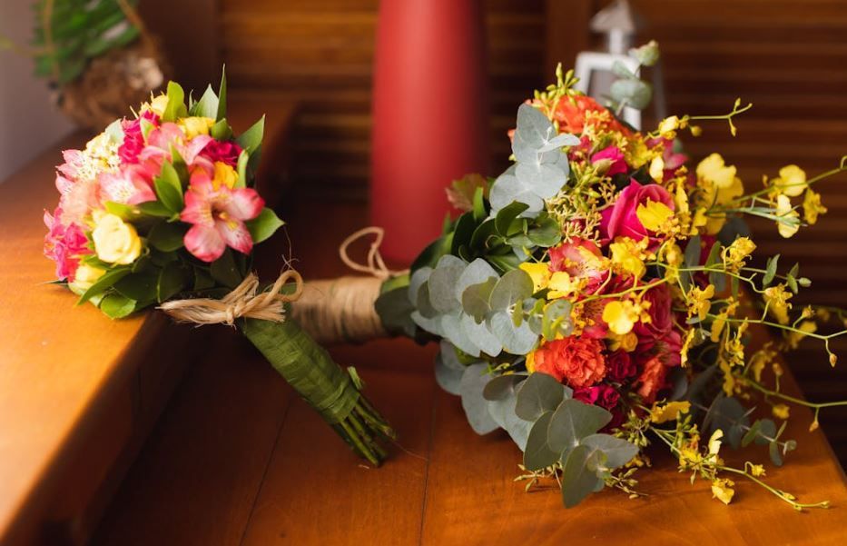 Two colorful bouquets with roses and eucalyptus on a wooden table, Oklahoma City, OK
