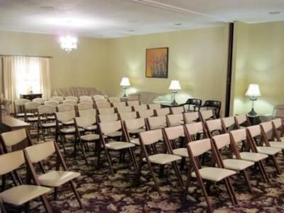 Rows of folding chairs set up in a softly lit room for an event or meeting.