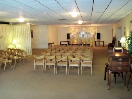 Empty banquet hall with rows of chairs, white draped walls, and warm ceiling lights