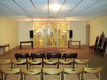 Empty hall with rows of chairs facing a small stage and decorative backdrop.