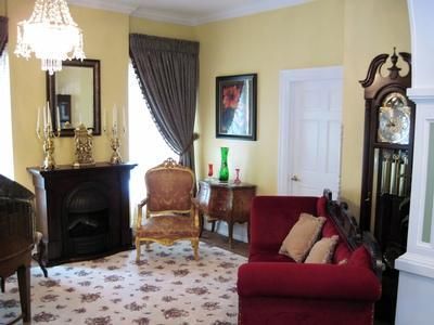 Elegant living room with fireplace, red sofa, armchair, patterned rug, and dark curtains.