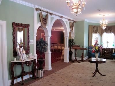 Elegant living room with arches, chandeliers, floral decor, and a round table by bright windows
