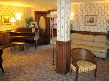 Vintage living room with a grand piano, beige sofa, and patterned wallpaper