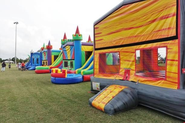 Colorful inflatable bounce houses and slides lined up on a grassy field at an outdoor event