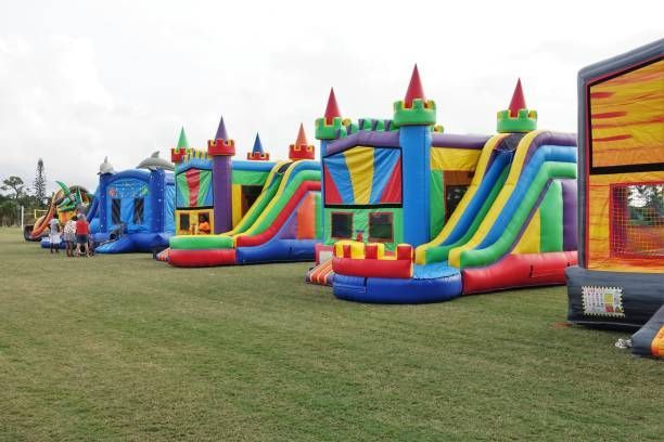 Colorful inflatable bounce houses and slides lined up on a grassy field at an outdoor event