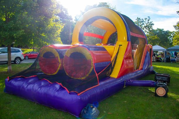 Colorful inflatable obstacle course with red tunnels and yellow arch on a grassy field outdoors