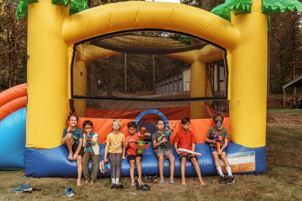 Children seated in front of a yellow and orange inflatable bounce house outdoors
