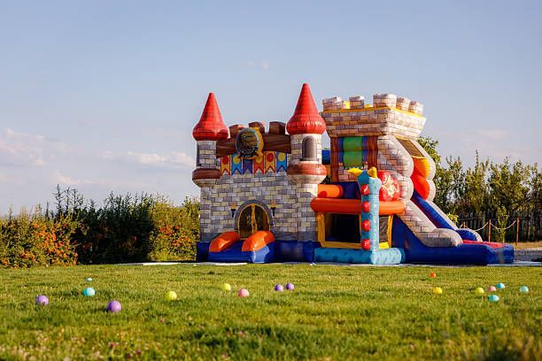 Colorful inflatable castle and slide on a grassy field under a clear sky