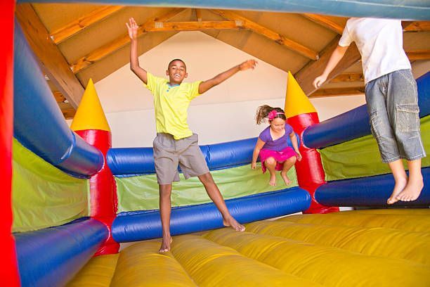 Children jumping inside a colorful inflatable bounce house with blue, red, and yellow walls