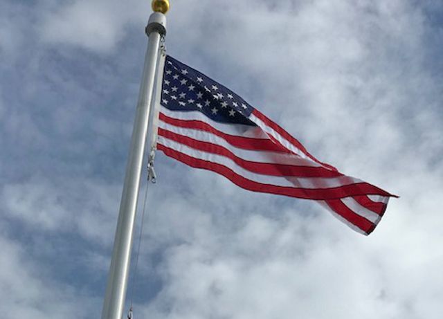 American flag waving on a pole against a cloudy sky