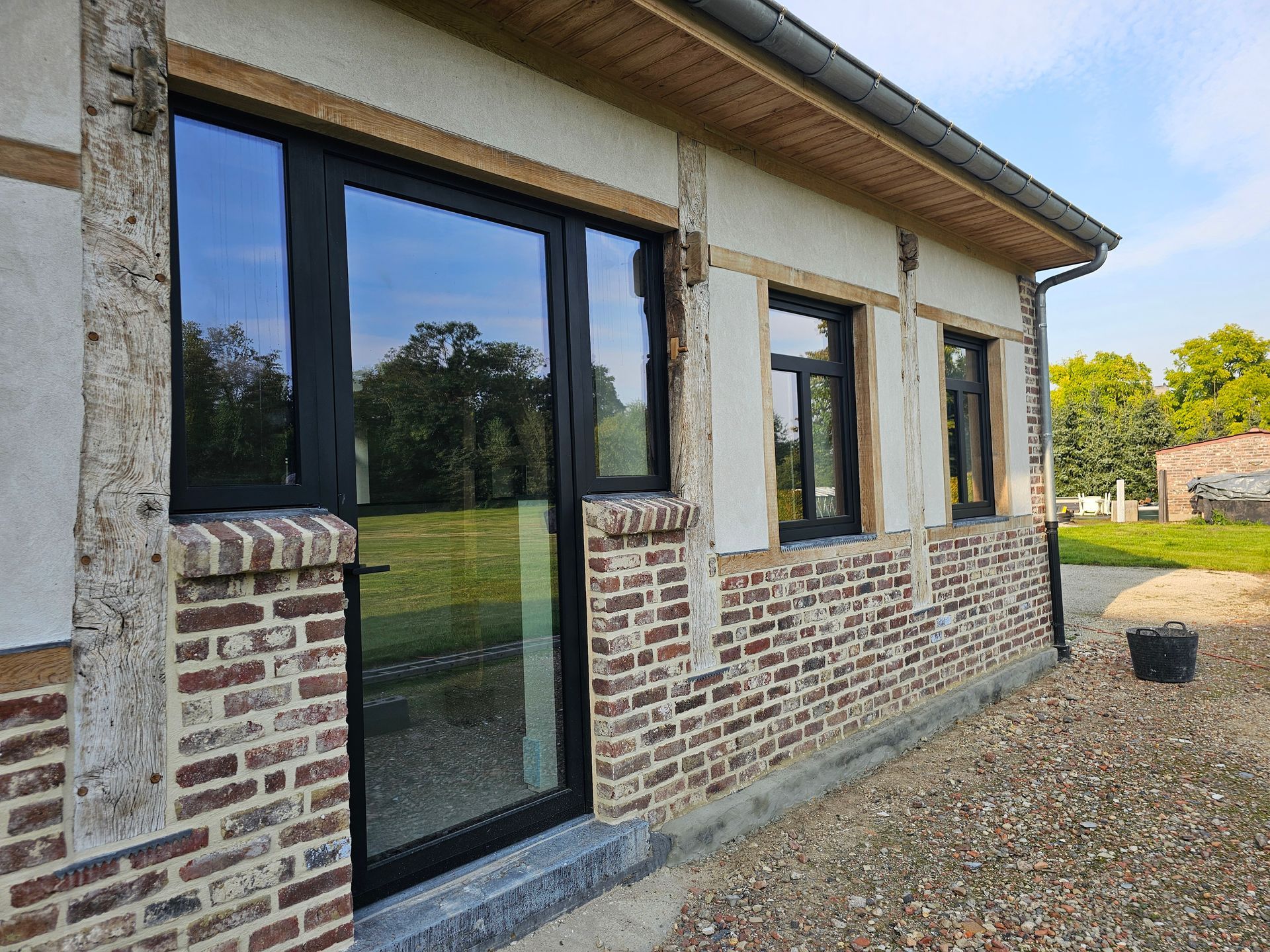 Detail van zwarte Reynaers aluminium raamprofielen tussen eiken balken