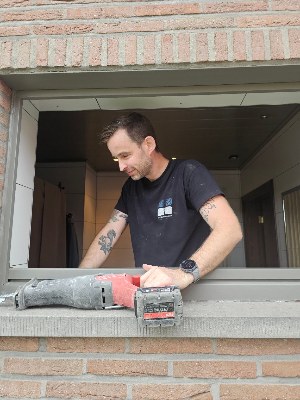 Steve van De Raammeester werkt aan een raam tijdens een renovatie in een bewoonde woning.