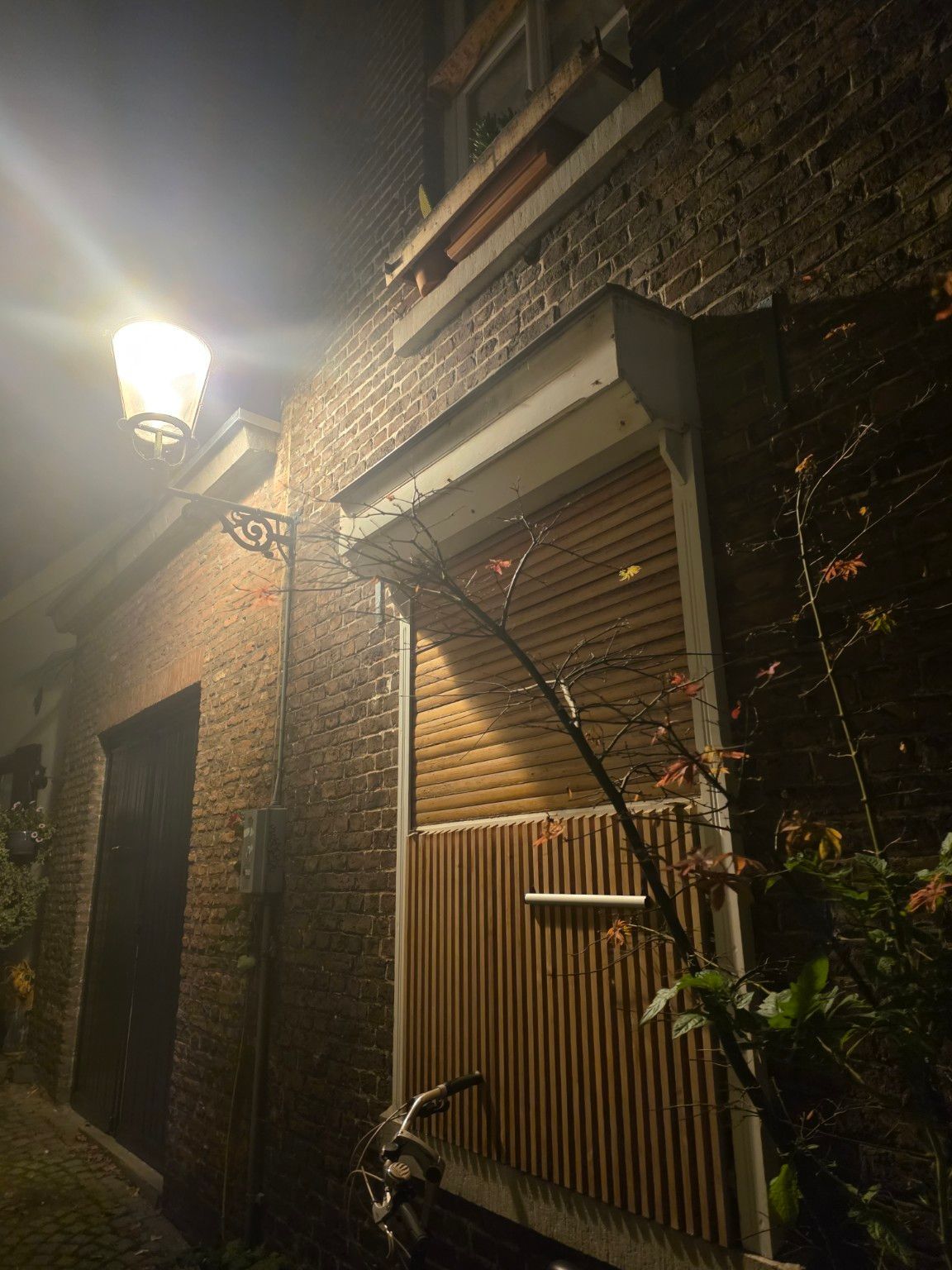 Oude rolluikkap boven een raam in een verlicht steegje in Maastricht