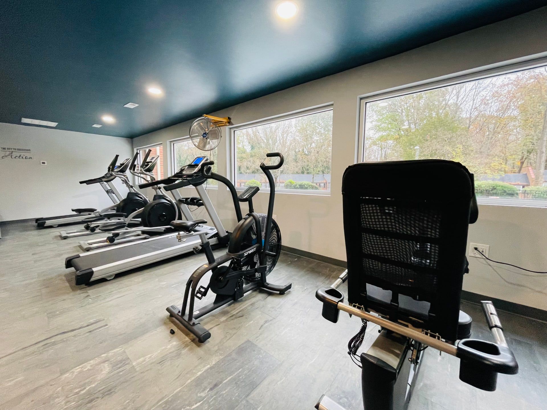 A row of treadmills and exercise bikes in a gym.