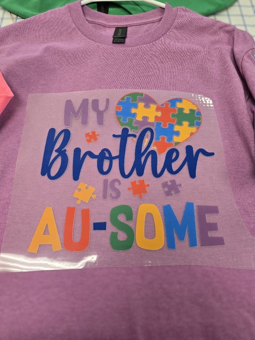 A purple sweatshirt with a colorful heart-shaped puzzle piece design and the text 