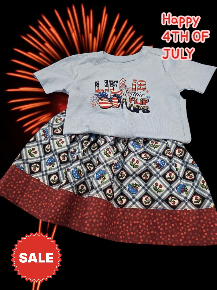 A light blue shirt and plaid skirt with a dark red border are displayed against a firework background for a 4th of July sale.