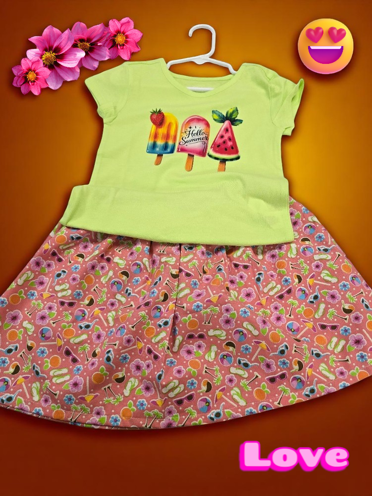 A light green t-shirt with three popsicle illustrations paired with a pink patterned skirt featuring summer-themed icons.