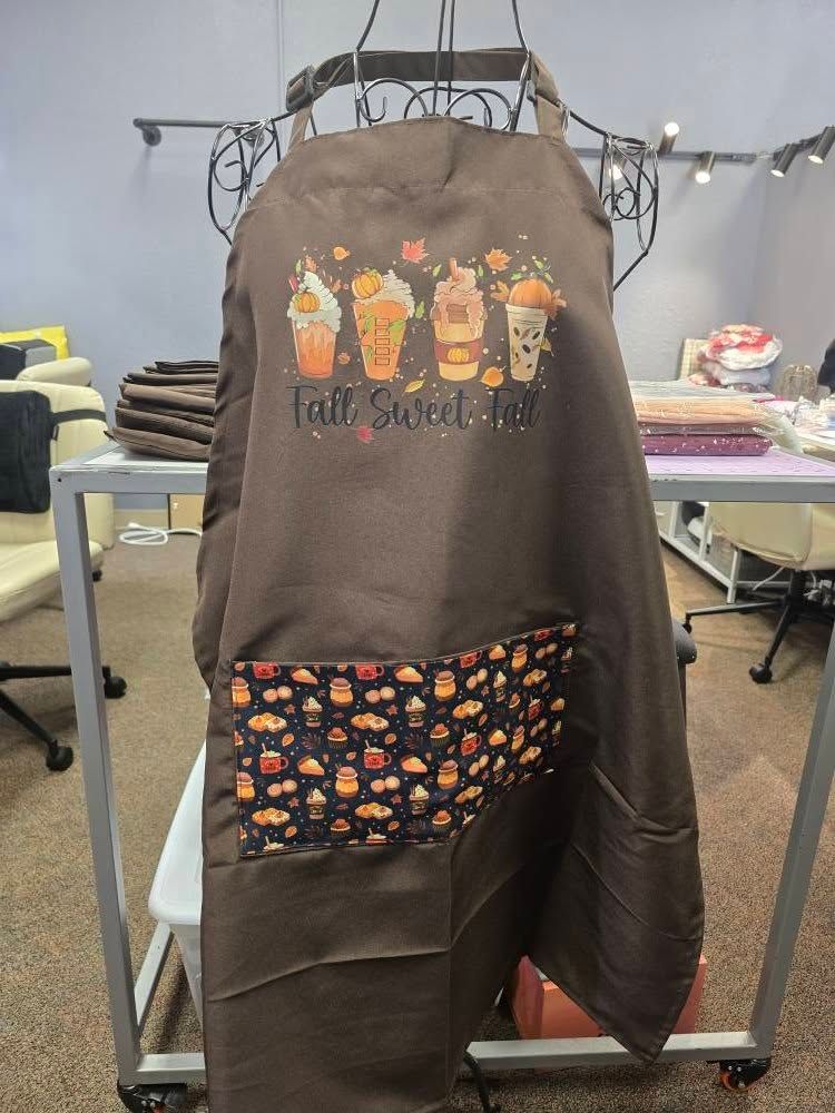 A brown apron with a printed graphic of four seasonal drinks above the text 