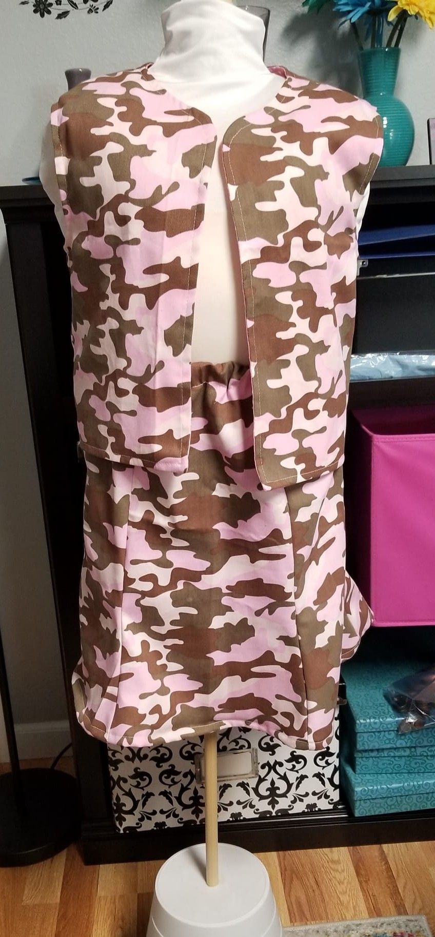 A two-piece pink and brown camouflage outfit displayed on a mannequin in a room.