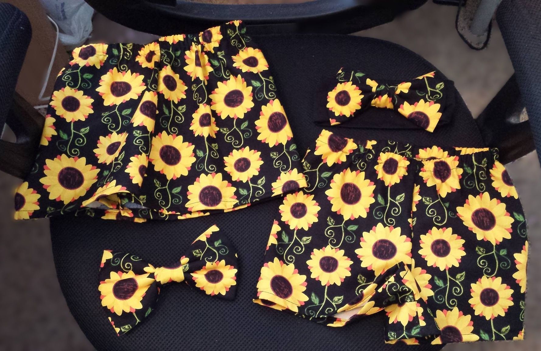 Matching items with a yellow sunflower print on a black background, including two bow ties, a skirt, and small shorts.
