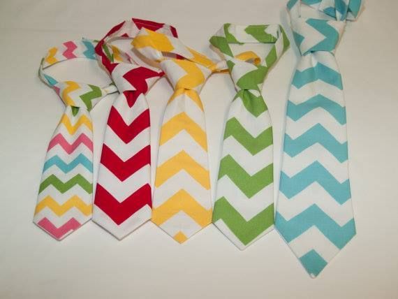 Five chevron-patterned ties in multicolored, red, yellow, green, and teal arranged side-by-side on a white background.