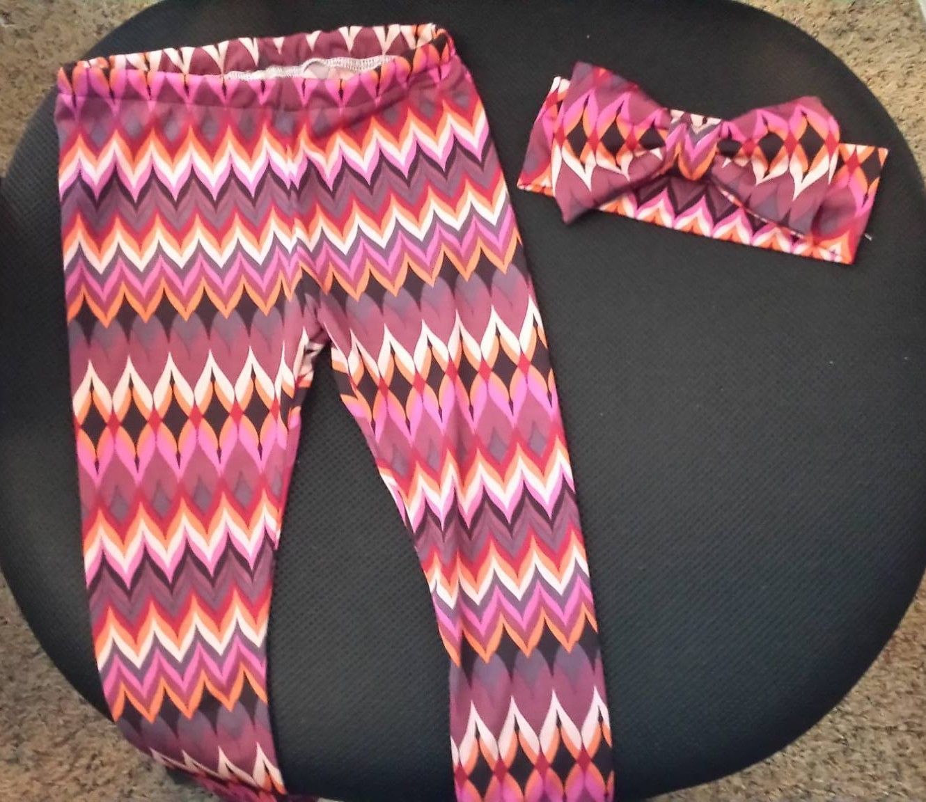Leggings and a matching headband featuring a colorful, geometric zigzag pattern in shades of pink, orange, and purple.