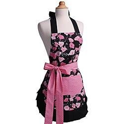 An apron with a pink and black floral pattern, a pink waist tie, and a black ruffled hem on a dress form.