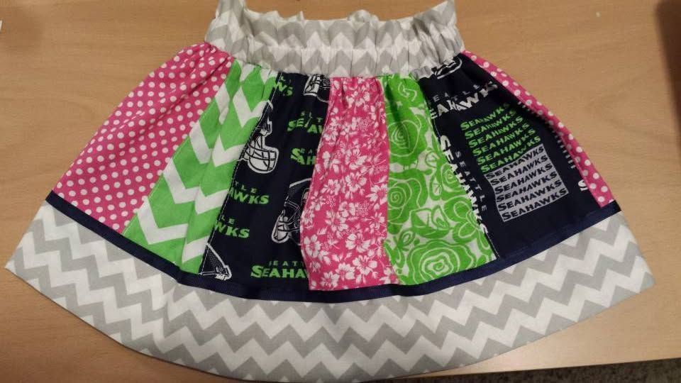 A colorful, patchwork-style toddler skirt featuring zig-zag patterns and Seahawks-themed fabric with a gathered waist.