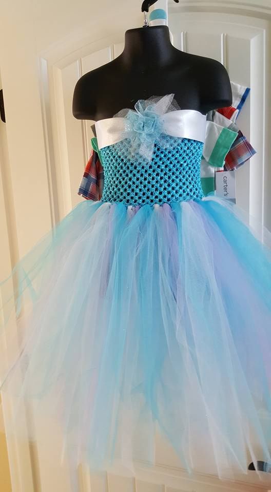 A turquoise crochet-top tutu dress with a white ribbon sash and layered light blue and white tulle skirt on a mannequin.